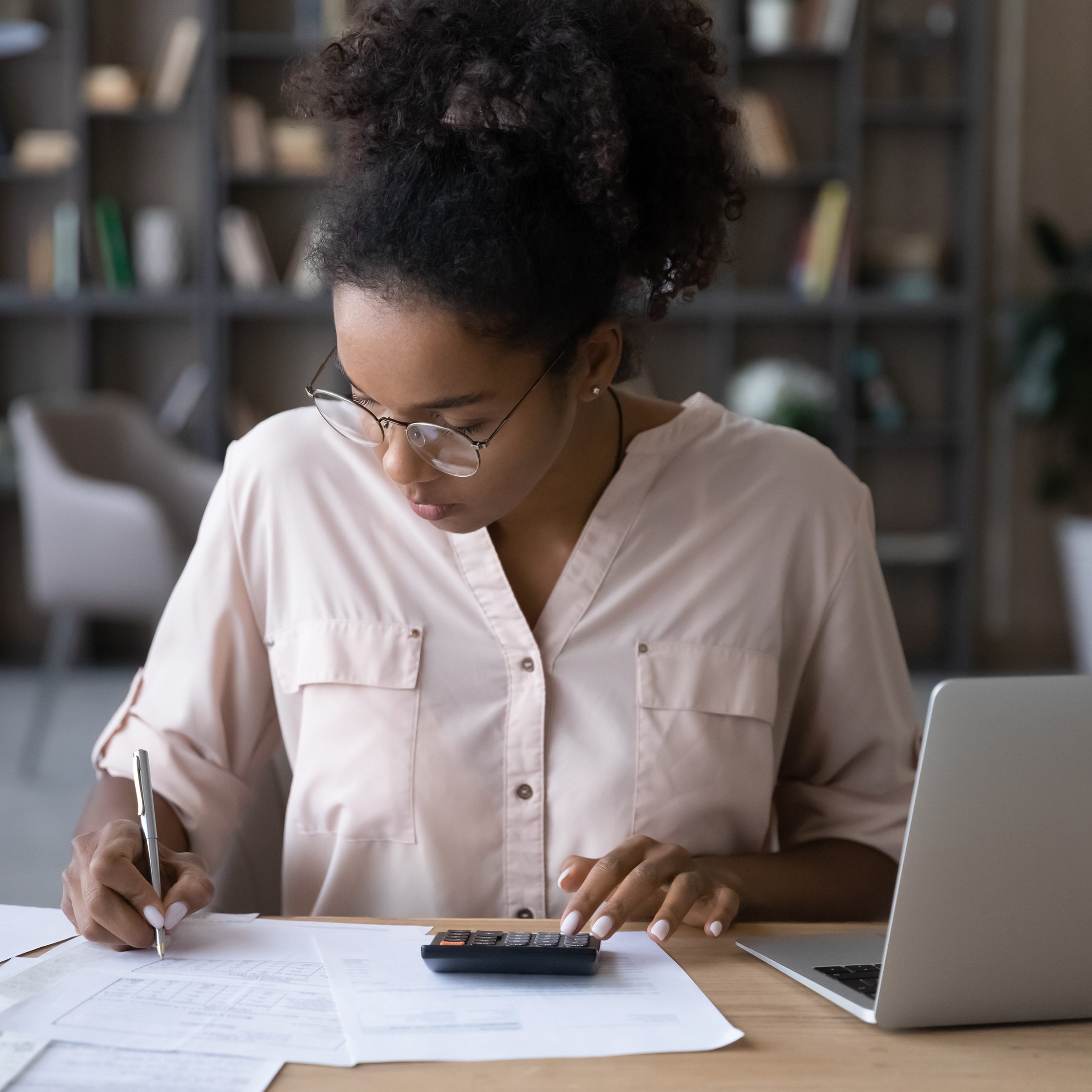 undergraduate accounting programs; Serious young biracial woman sit at desk undergraduate programs in accounting online on laptop.