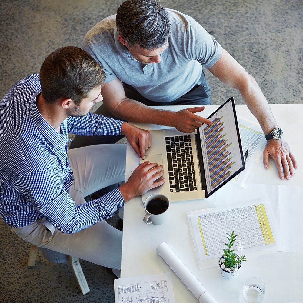Undergraduate program in marketing, marketing analytics concentration. Two people at a desk reviewing a chart of data on a computer screen.