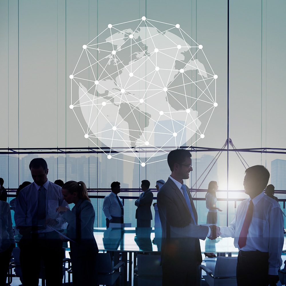 Management Programs: International Business. Group of international businesspeople meeting in a boardroom with a diagram of the earth and a general city skyline in the background.
